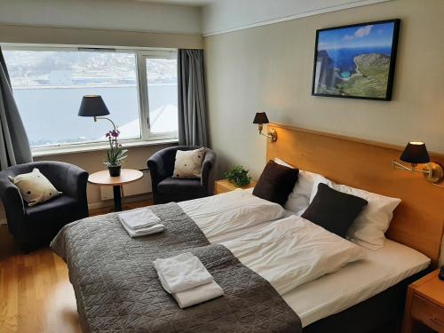 Bremanger Fjord Hotell في Svelgen: غرفة نوم بسرير كبير وكرسيين