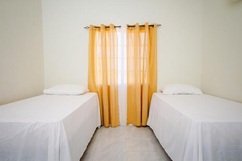 two beds in a room with orange curtains at home with relaxing sea view in Discovery Bay