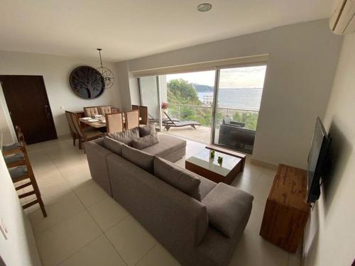 曼萨尼约HERMOSO DEPARTAMENTO DE LUJO EN MANZANILLO A PIE DE PLAYA EN PONTO HORIZONTE MANZANILLO. PARA HASTA 8 PERSONAS, DE LO MEJOR DE MANZANILLO. HERMOSA VISTA AL MAR的客厅里有一张沙发、一张桌子和一台电视