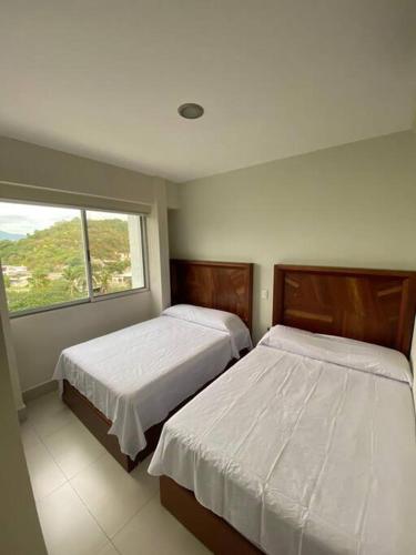 a bedroom with two beds and a window at HERMOSO DEPARTAMENTO DE LUJO EN MANZANILLO A PIE DE PLAYA EN PONTO HORIZONTE MANZANILLO. PARA HASTA 8 PERSONAS, DE LO MEJOR DE MANZANILLO. HERMOSA VISTA AL MAR in Manzanillo