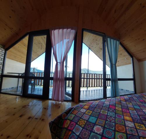 a bedroom with large windows and a bed in a room at Happy days house in Shuakhevi