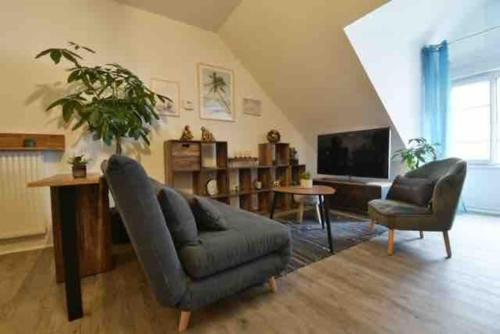 a living room with a couch and a television at Appartement BELLO , ruelle au cœur de ville, arrivée en autonomie in Lons-le-Saunier