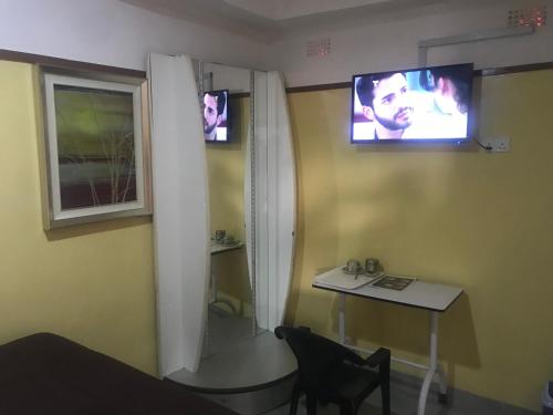 um quarto com uma mesa e uma televisão na parede em Awesome Executive Lodge em Solwezi