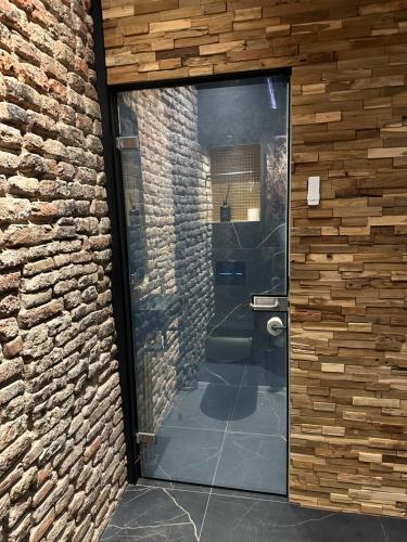 a bathroom with a glass door in a brick wall at Hotel de Prince in Nijmegen