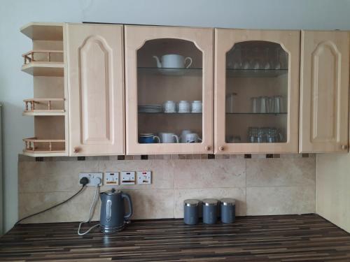 una cocina con armarios de madera con platos y platos en 47R Place, en Dagenham