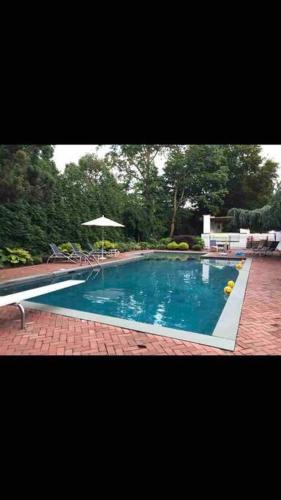 a swimming pool with an umbrella and a brick floor at Resort type home in Old Brookvile !!! in Glen Head