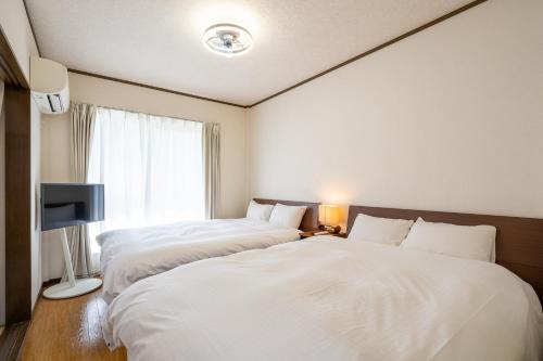 2 camas en una habitación de hotel con sábanas blancas en maison elegance - Vacation STAY 15341, en Tokio