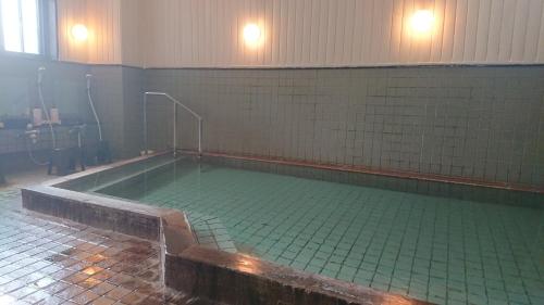 a large swimming pool with green tiled walls at Daikokuya Ryokan - Vacation STAY 53558v in Hakodate
