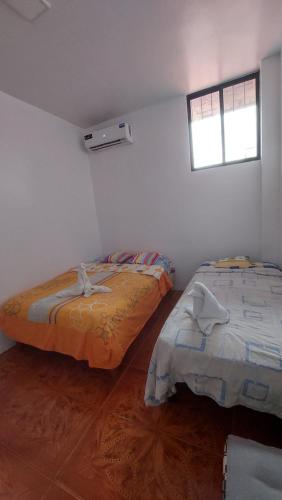two beds in a white room with a window at CASA DE NOELIA in Puerto Baquerizo Moreno