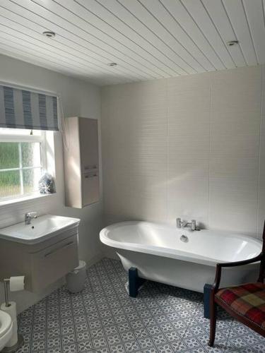 a white bathroom with a tub and a sink at Millview Cottage in Castledawson