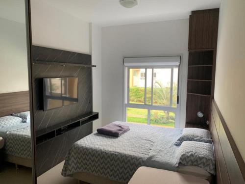 1 dormitorio con espejo, cama y ventana en Apartamento na Praia do Campeche, en Florianópolis