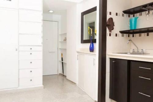 a kitchen with white cabinets and a sink and a mirror at Caribbean Ocean view at the hotel zone in Cancún
