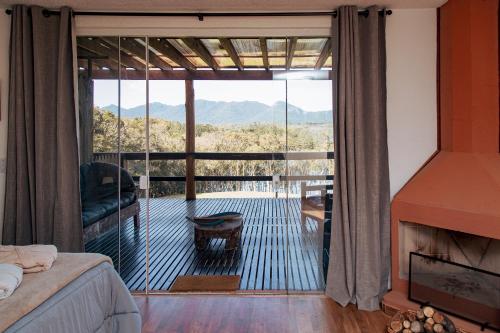 a bedroom with a large glass door to a balcony at Chácara Caminho das Águas in Piraquara