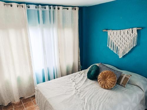 a bedroom with a bed with blue walls and a window at Casa Selva in Cabuya