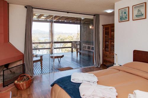 1 dormitorio con 1 cama y balcón con vistas. en Chácara Caminho das Águas, en Piraquara