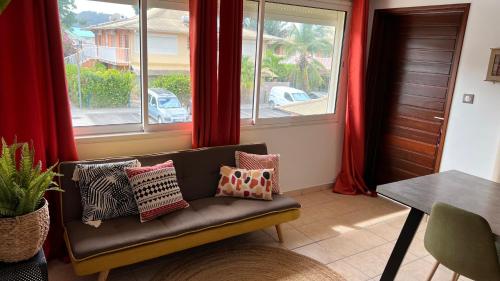 een woonkamer met een bank en een raam bij F2 rénové, climatisé et lumineux in Cayenne