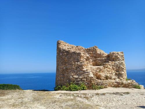 an old stone building on top of a hill next to the ocean at Da Tziu Efisiu Mare e Relax nel Sinis in Baratili San Pietro
