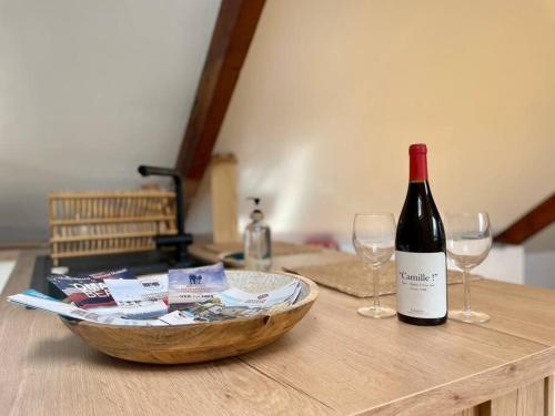 a bottle of wine and two wine glasses on a table at La Bellevue x Parking by Melrose in Bayeux
