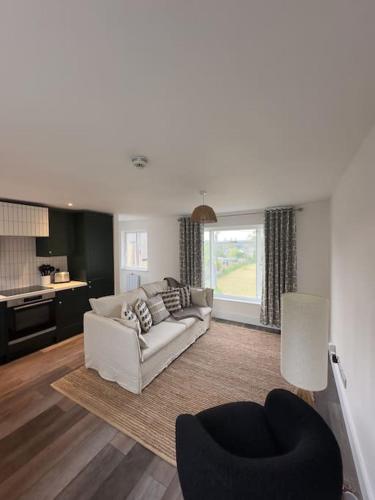 a living room with a white couch and a chair at Chic Barn Conversion in the Cotwolds in Enstone