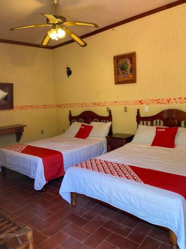 a bedroom with two beds with red and white sheets at Rancho Hotel El Carmen in Tlapacoyan