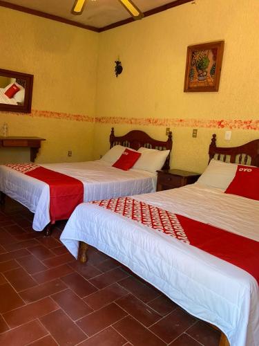 a room with two beds with red and white sheets at Rancho Hotel El Carmen in Tlapacoyan