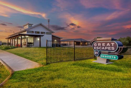 a sign in the grass in front of a house at Great Escapes RV Resort Bryan College Station in Bryan