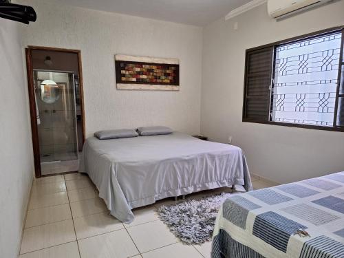a bedroom with a bed and a window and a shower at Casa de temporada Uberaba piscina in Uberaba
