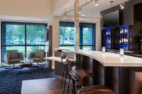 a kitchen with a bar with chairs and windows at Courtyard by Marriott West Palm Beach in West Palm Beach