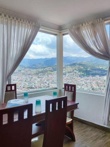 comedor con mesa y sillas y ventana grande en Departamento acogedor y moderno, vista increíble., en Loja