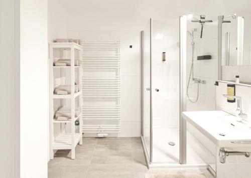 ein weißes Bad mit einer Dusche und einem Waschbecken in der Unterkunft Deichstadt Apartments in Neuwied