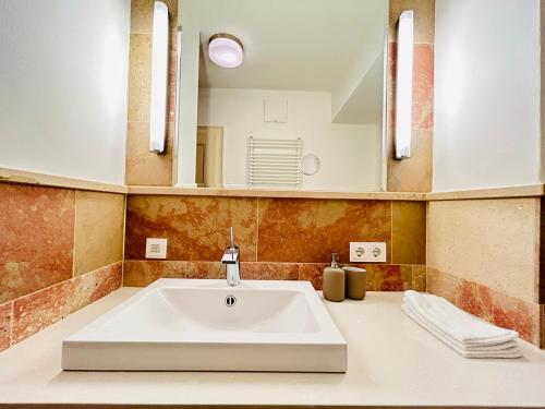 ein Badezimmer mit einem weißen Waschbecken und einem Spiegel in der Unterkunft Palais am Kai - Zentrale Lage, Kostenloser Parkplatz in Salzburg
