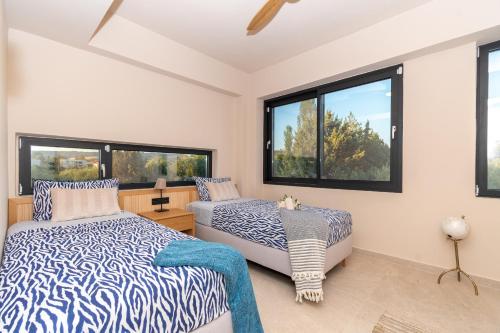 a bedroom with two beds and two windows at SithoniaRS Luxury Three Floors Villa With Private Pool & Garden in Nikiti