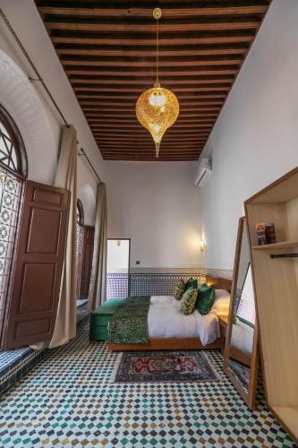 a bedroom with a bed and a chandelier at Riad Fes Ziyat & Spa in Fès