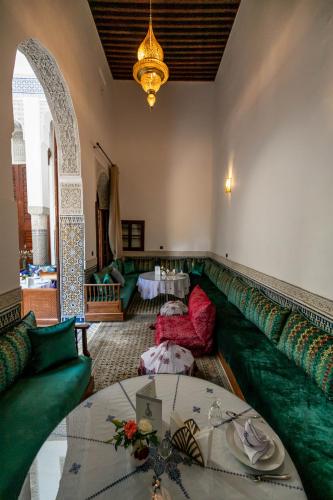 a living room with a green couch and a table at Riad Fes Ziyat & Spa in Fès