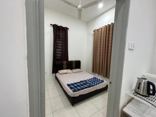 ein kleines Zimmer mit einem Bett in der Ecke eines Zimmers in der Unterkunft Homestay Cermai Indah Guar Chempedak in Guar Chempedak