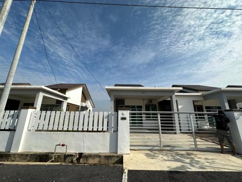 a man standing in front of a house with a fence at Homestay Cermai Indah Guar Chempedak in Guar Chempedak