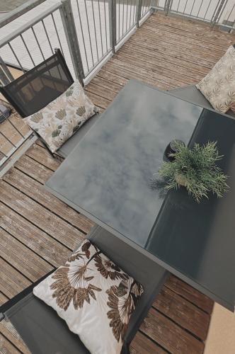 a glass table on a deck with pillows and a plant at Deichstadt Apartments in Neuwied