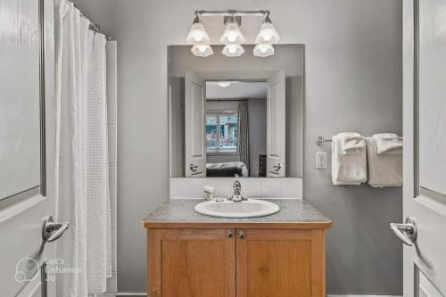 een badkamer met een wastafel en een spiegel bij 2BR Condo in Canmore [Pool, 3 Hot Tubs, Gym & BBQ] in Canmore