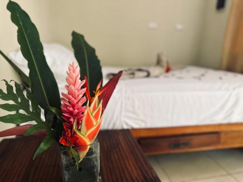 een vaas met bloemen op een tafel met een bed bij Samana tropical in Santa Bárbara de Samaná