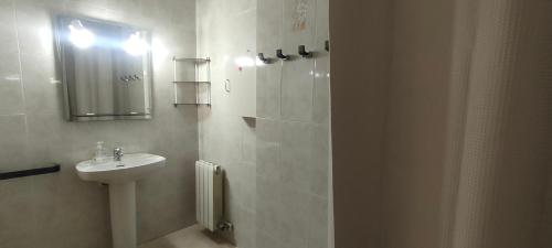 La salle de bains blanche est pourvue d'un lavabo et d'un miroir. dans l'établissement Casa Miravent, à Bellvei del Penedes