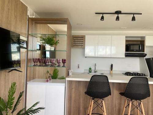a kitchen with two bar stools in front of a counter at Apartamentos Avenida del malecón, frente al lago. Guatape in Guatapé