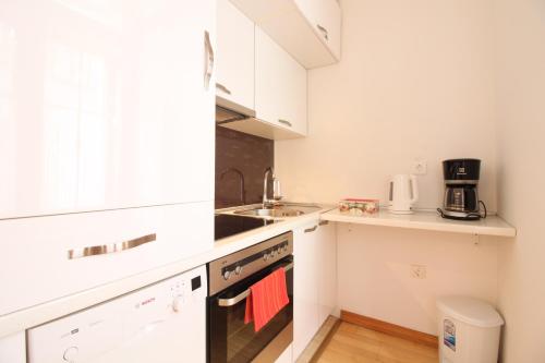 una pequeña cocina con armarios blancos y fregadero en City Studio Apartment, en Sarajevo