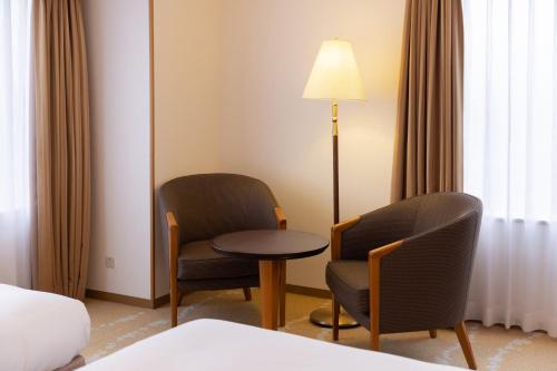 a hotel room with two chairs and a table and a lamp at ANA Crowne Plaza Toyama by IHG in Toyama