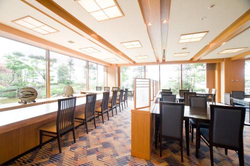 a dining room with tables and chairs and windows at ANA Crowne Plaza Toyama by IHG in Toyama
