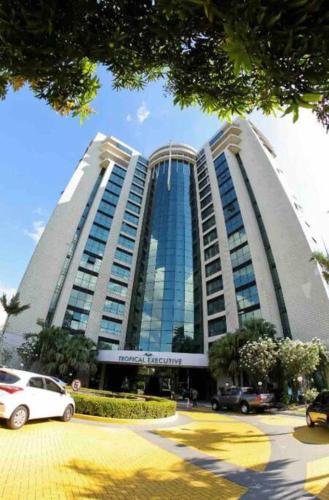 a large building with cars parked in front of it at Flat em Tropical Executive Hotel in Manaus