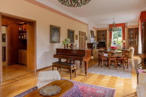 a living room with a piano and a dining room at Villa Volpe Como in Lanzo dʼIntelvi
