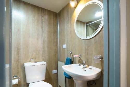 W łazience znajduje się toaleta, umywalka i lustro. w obiekcie Amanecer de la Bahía w mieście Ushuaia