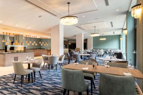 a restaurant with tables and chairs and a bar at Hilton London Gatwick Airport in Horley
