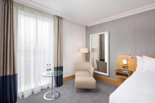 a hotel room with a bed and a chair and a table at Hilton London Gatwick Airport in Horley