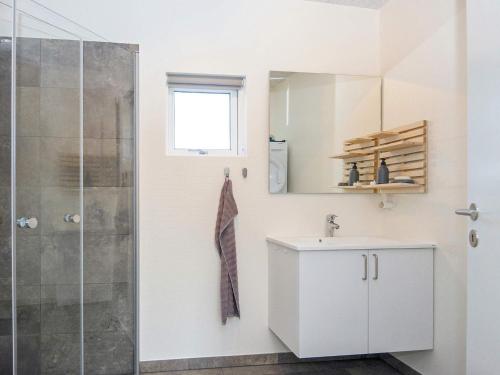 a white bathroom with a shower and a sink at Holiday home Ringkøbing LXXX in Ringkøbing